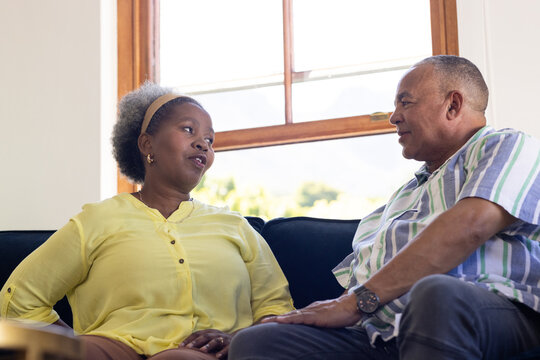 African American senior couple sitting on couch, having heartfelt conversation