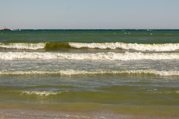 Scenic seascape of gentle waves reaching the sandy shoreline with a bright blue sky in the background