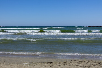 Scenic seascape of gentle waves reaching the sandy shoreline with a bright blue sky in the background