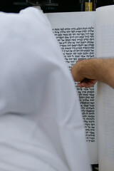 A bar mitzvah boy reading from the Torah scroll in a synagogue.