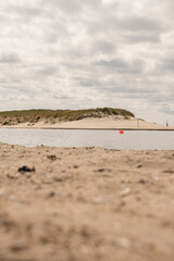 Bright sandy shoreline with calm water reflecting clouds in a coastal setting during daytime