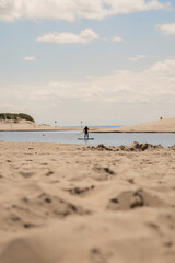 Person paddleboarding on calm water near sandy shore under cloudy sky during late afternoon