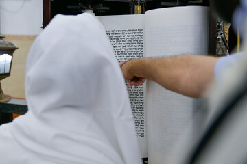 A bar mitzvah boy reading from the Torah scroll in a synagogue.