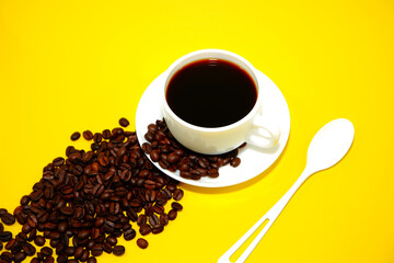 Coffee cup with coffee beans closeup shot on yellow background close-up view 
