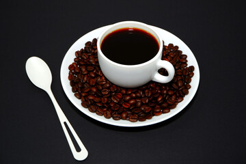 Coffee cup with coffee beans closeup shot on black background 