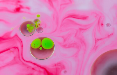 Close up view of abstract pink and green intriguing liquid art paint swirls combination, marble texture wallpaper background.