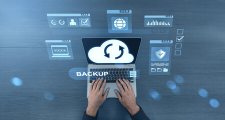 Cloud backup concept with laptop and virtual icons on dark wooden background.
