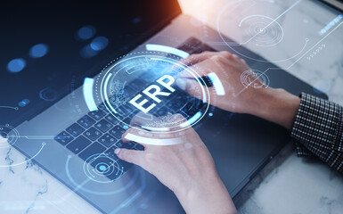 Hands typing on laptop with digital ERP interface concept on futuristic blue overlay background representing enterprise resource planning system.