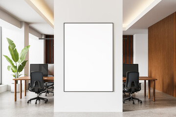 Modern office interior with blank poster mockup on white wall in front of wood-accented workspace and ergonomic chairs. 3D Rendering