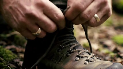 Hands tying laces on hiking boots amidst a natural, rugged outdoor setting, emphasizing preparation for adventure. - Powered by Adobe