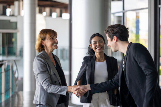 Business team from diverse cultures, genders, and generations celebrate the success hitting targets. Group of office workers express their appreciation to each other at the balcony. Cross generations