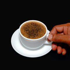 cup of coffee picking by hand close up view on black background 