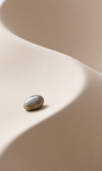 Minimalist still life with a natural pebble on a gracefully curved beige surface, a concept of harmony and simplicity