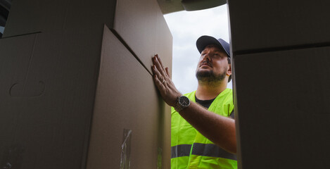 Low-angle shot of delivery boy taking boxes out of his van. He is wearing all PPE.