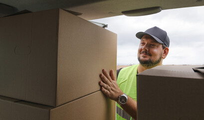 Delivery guy smiling as he takes boxes out of his van. He's wearing all the PPE. Copy space
