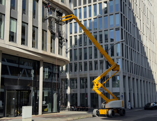 Cleaner worker using a cherry picker to clean a glas facade of a contemporary office building © Jarama