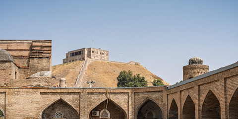 Landscape view of ancient madrasa kunha with Hissar aka Hisor fortress in background, historic medieval landmark of Tajikistan	
