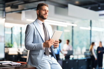 Young modern business man working using digital tablet while sitting in the office