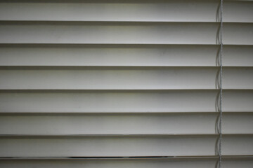 Calm white horizontal blind window close up view. simple texture background with pattern of straight parallel line and shadow creating private