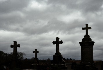 Medieval stone crosses from an ancient cemetery silhouetted against a dramatic cloudy sky at sunrise.