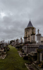 Obraz premium Cloudy day in a historic medieval French cemetery with tombs and stone crosses with a tower of the Carcassonne fortress in the background.