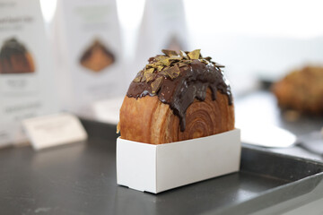 Cromboloni with chocolate topping coating on top. Chocolate Croissant with blurred background.