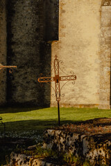 Medieval wrought iron cross in a sunlit cemetery at the golden hour of sunset.