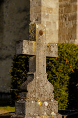 An old stone cross covered with lichens illuminated by the evening light in an ancient cemetery.