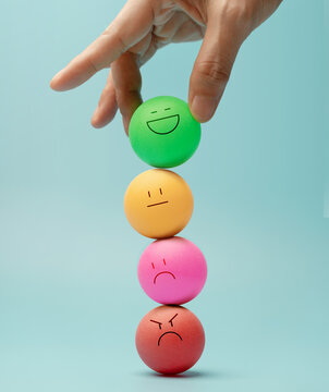 Hand balancing Colorful emotional faces Ball, symbolizing mental health and emotional self-regulation through balancing positive and negative emotions