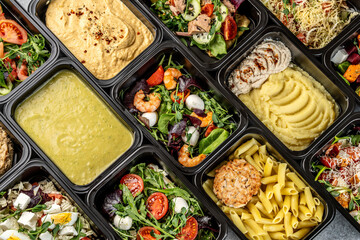 Assorted healthy meal prep containers with salads, pasta, mashed potatoes, and hummus