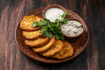 Potato pancakes with sour cream and mushroom sauce on a rustic plate