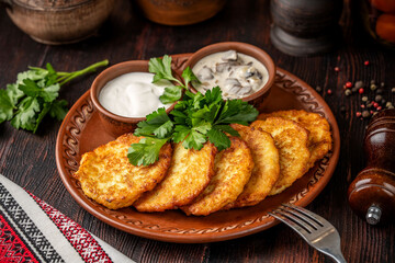 Traditional potato pancakes with sour cream and mushroom sauce on a rustic plate