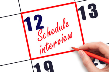 12 th day of the month.  Hand writing Schedule interview reminder and drawing red frame on calendar with red pen on white background. Business concept. Planning and scheduling