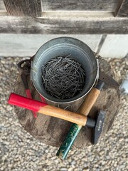 Bucket of Nails and Hammers on Rustic Wooden Stool
