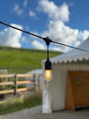 Vintage-Style String Light Against Blue Sky in Countryside
