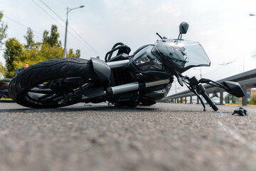The motorcycle lies on the sidewalk after a ride. Serious accident. Accident, close-up. Lost control and fell. Driving hazards. Collisions with another vehicle.