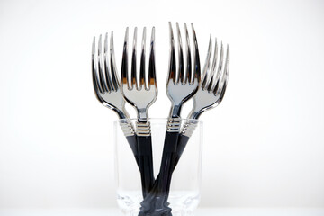 Silver forks together on glass bowl closeup view 