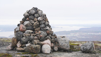 A stone covered with moss in the tundra against the backdrop of the bay and ships. 