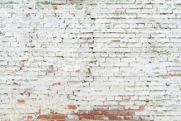 Close up of very old brick wall with cracked white peeling paint texture