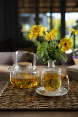 Relaxing tea time with herbal tea and vibrant flowers in a cozy indoor setting during afternoon light
