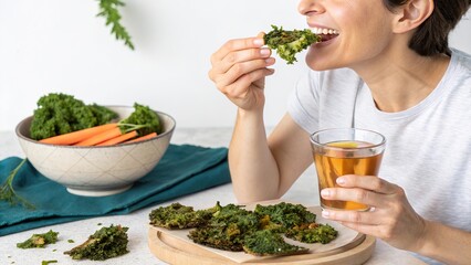 Crispy homemade veggie chips enjoyed by a woman in a cozy kitchen setting with a refreshing drink