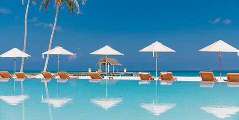 Obraz na płótnie Canvas Stunning luxury resort infinity pool with lounge sunbeds and umbrellas, palm trees and sea view reflections, tropical island paradise perfect for summer vacation and exotic travel. Tourism wall art