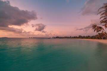 Majestic sunset over tropical island bay in Maldives with palm tree silhouettes, calm sea and serene seascape, colorful sky and peaceful ocean horizon, perfect for summer vacation, travel, and tropica