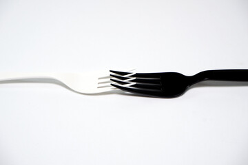 Black and white forks combined together on white background close-up view 