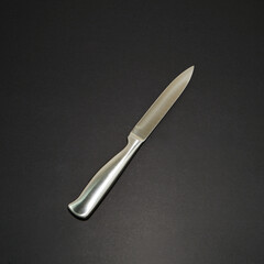 A metal knife on black background closeup view 