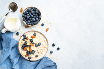 Oatmeal porridge with milk, bananas and blueberries. Flat lay with copy space.