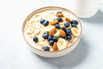Oatmeal porridge with bananas, nuts and blueberries. Healthy breakfast.