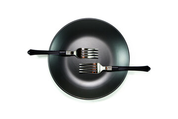 silver forks together placed above black ceramic plate  close up view flat lay photography white background