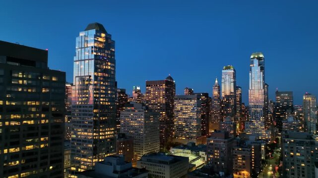 Cityscape at dusk with building lights against a dark blue sky
