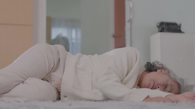 An elderly Asian female patient fainted and fell to the floor at home and was helped charming physical therapist nurse in living room. High or low blood pressure, diabetes, heart disease. Older care.